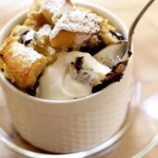 Spoon taking a bite of a Banana Bread Pudding with Chocolate Chunks drizzled with lightly whipped whipped cream