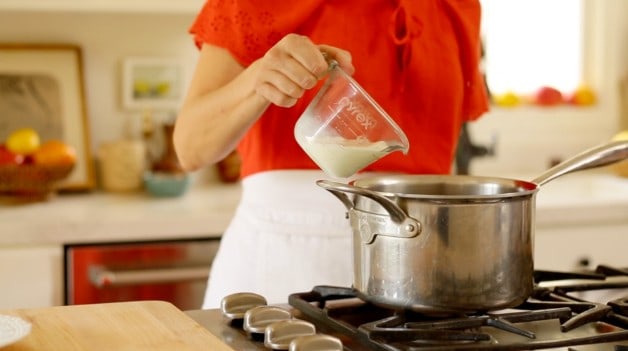 Pouring cream into large pot on stove