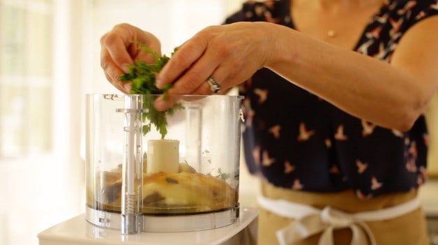 placing parsley and eggplant in a food processor