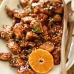 A platter of chicken with orange chicken sauce and sliced mandarin oranges.