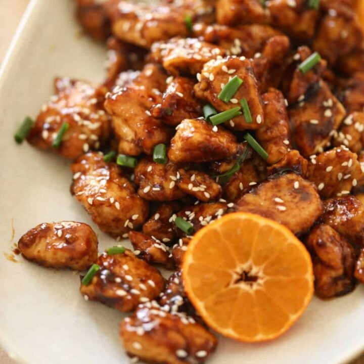 Orange chicken on a platter with a sliced mandarin