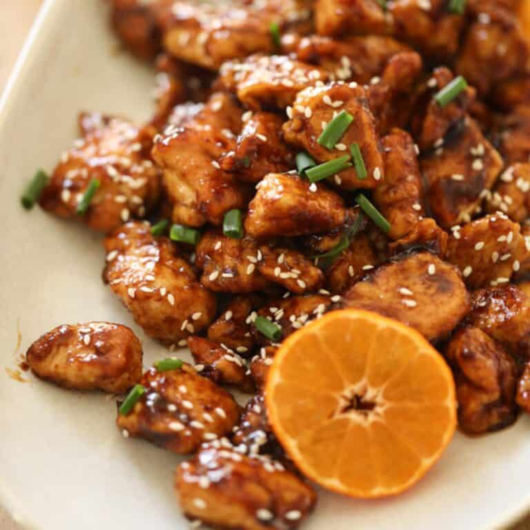 Orange chicken on a platter with a sliced mandarin