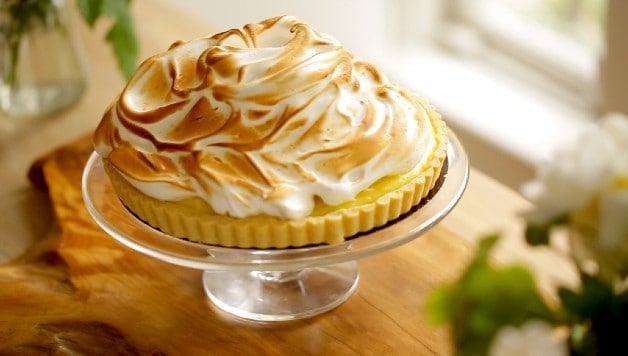 Lemon Meringue Tart on cake stand resting on wooden board