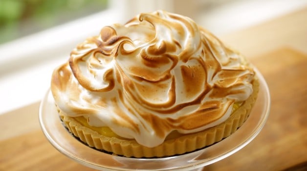 Top-down view of toasted Meringue on top of a Lemon Meringue Tart on a clear glass cake stand