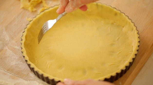 fork pricking tart dough in a tart dish