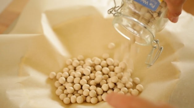 Pouring Baking beads into a tart shell covered with parchment paper 