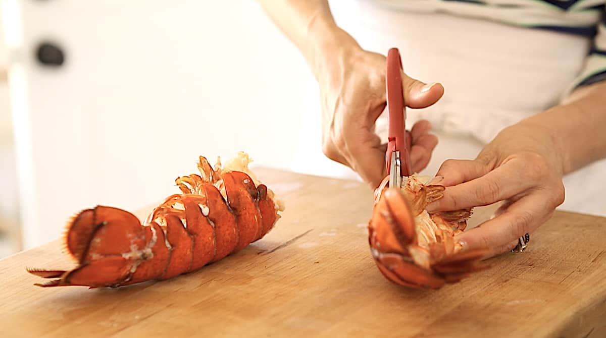 a person cutting open a cooked lobster tail