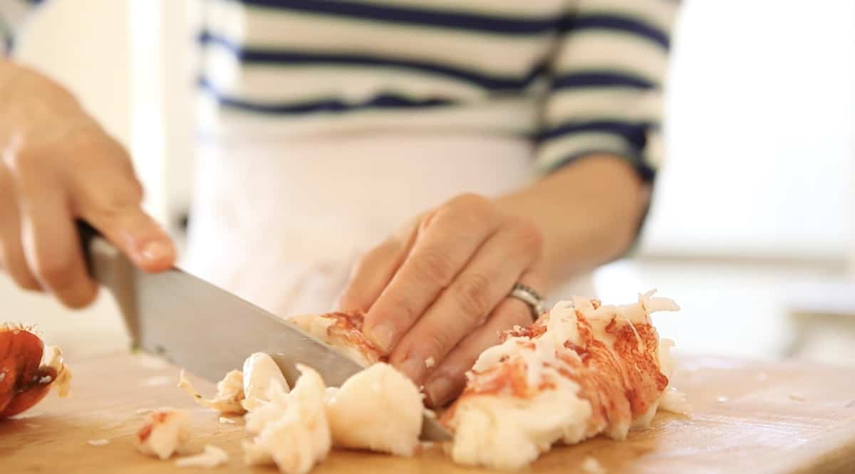 a person cutting cooked lobster into chunks