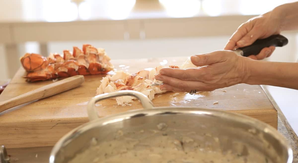 adding cooked lobster pieces into a skillet with lobster thermidor sauce