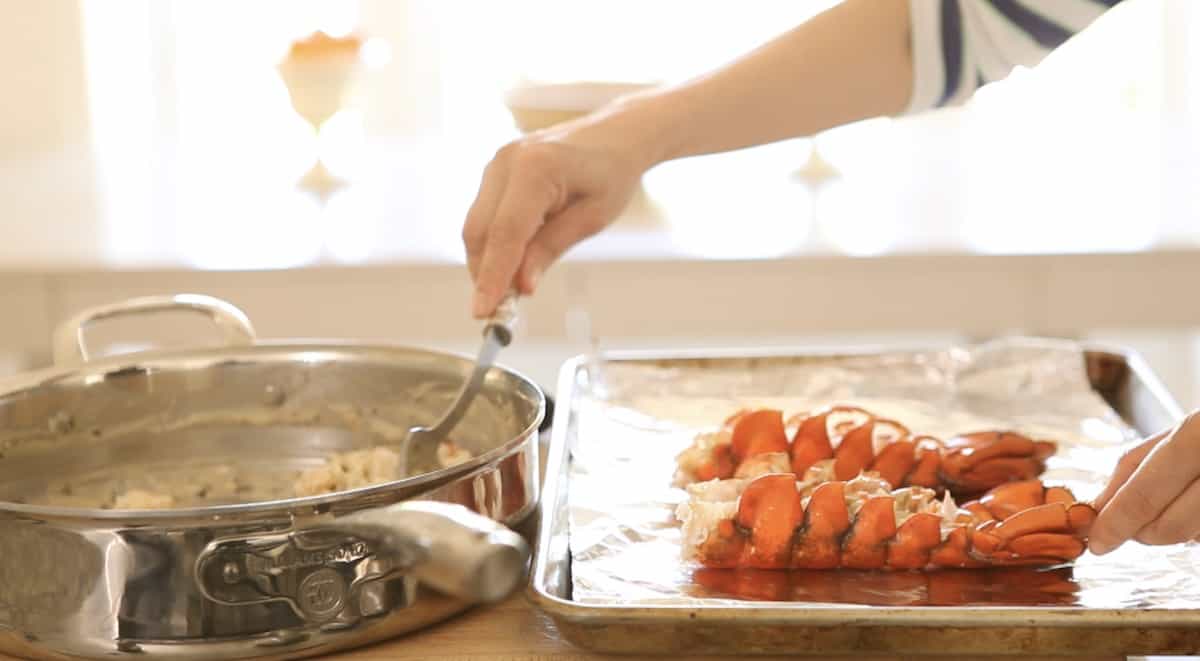 a person spooning lobster thermidor sauce into lobster shells