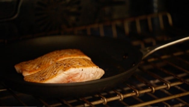 Salmon seared in a pan going in the oven