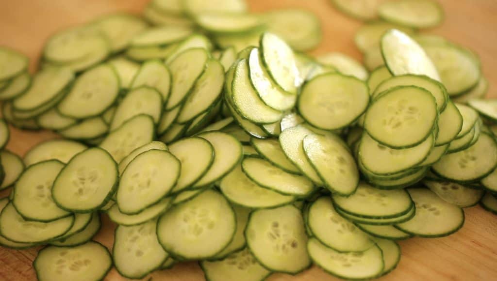 A pile of sliced cucumbers on a cutting board 