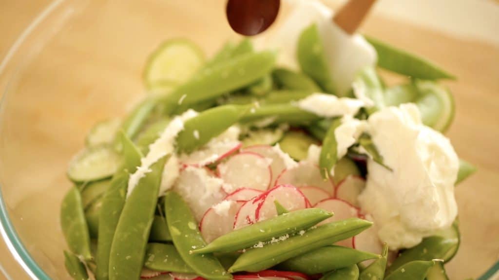 Mixing snap peas, radishes and cucumbers with sour cream
