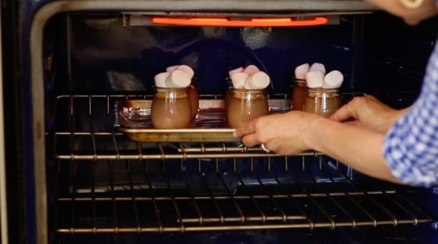 Toasting a pan of pudding pots with marshmallows under the oven\'s broiler