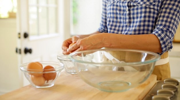 A person cracking an egg into a bowl