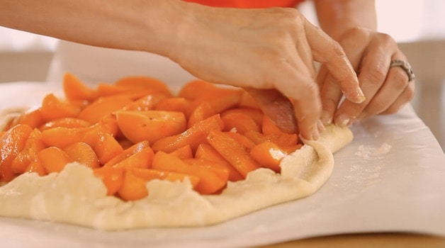 crimping the galette dough around the perimeter to form a crust