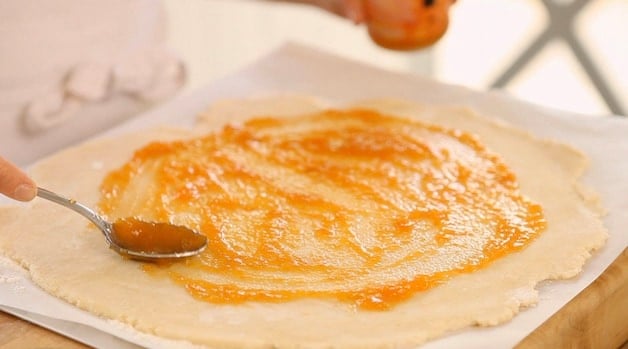 Spreading apricot jam on galette dough