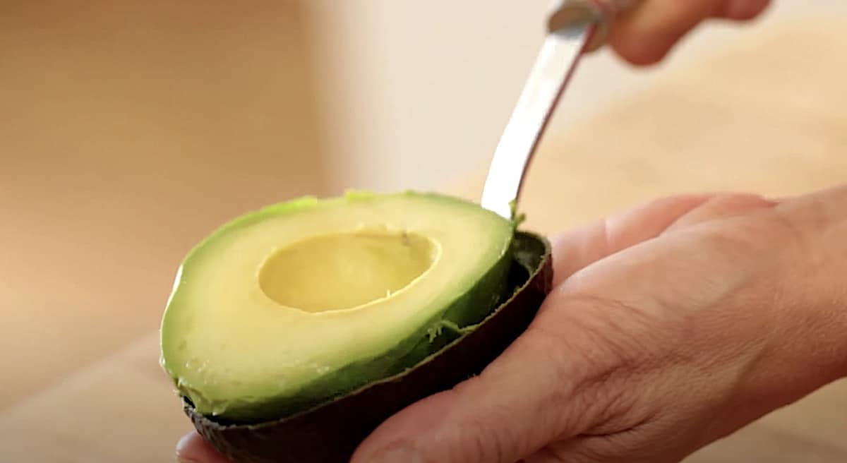 A person scooping an avocado from its shell