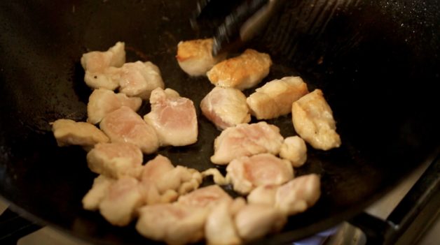 Browning pieces of chicken in a wok 