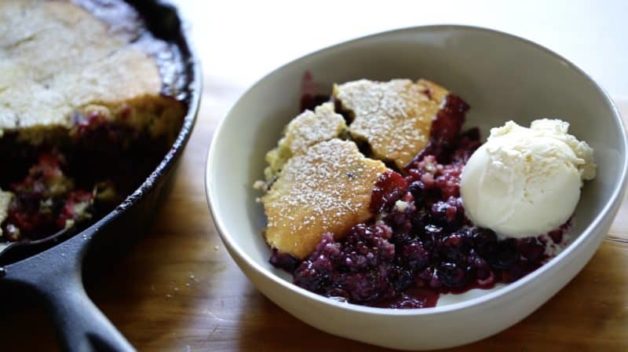 Triple Berry Campfire Cake Recipe in a cast-iron skillet with a serving portioned out in a bowl