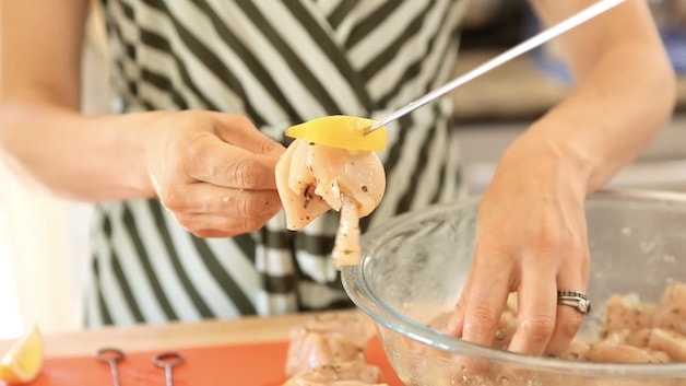 Threading chicken breast and lemon onto skewers