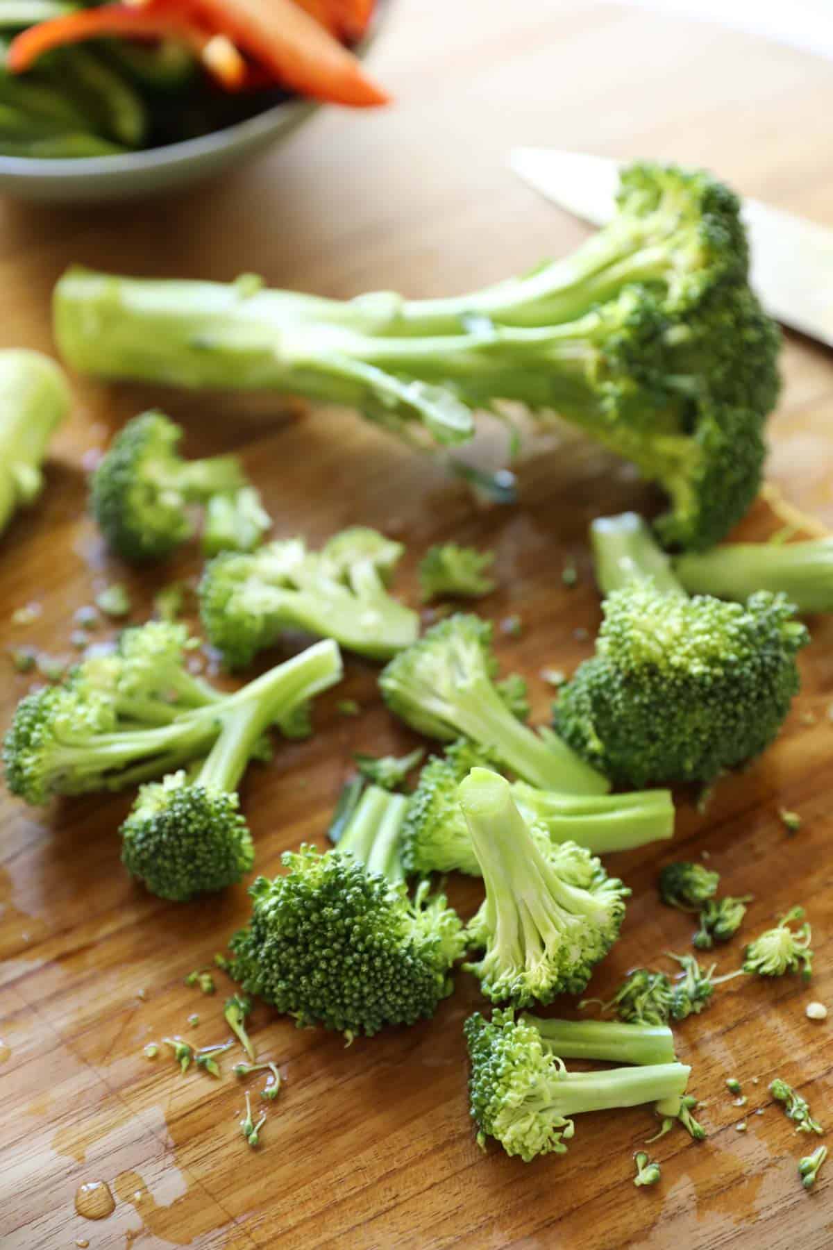 a head of broccoli cut into florets on a cutting board