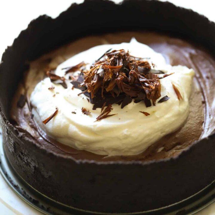 A chocolate mousse cake with chocolate cookie crust and whipped cream