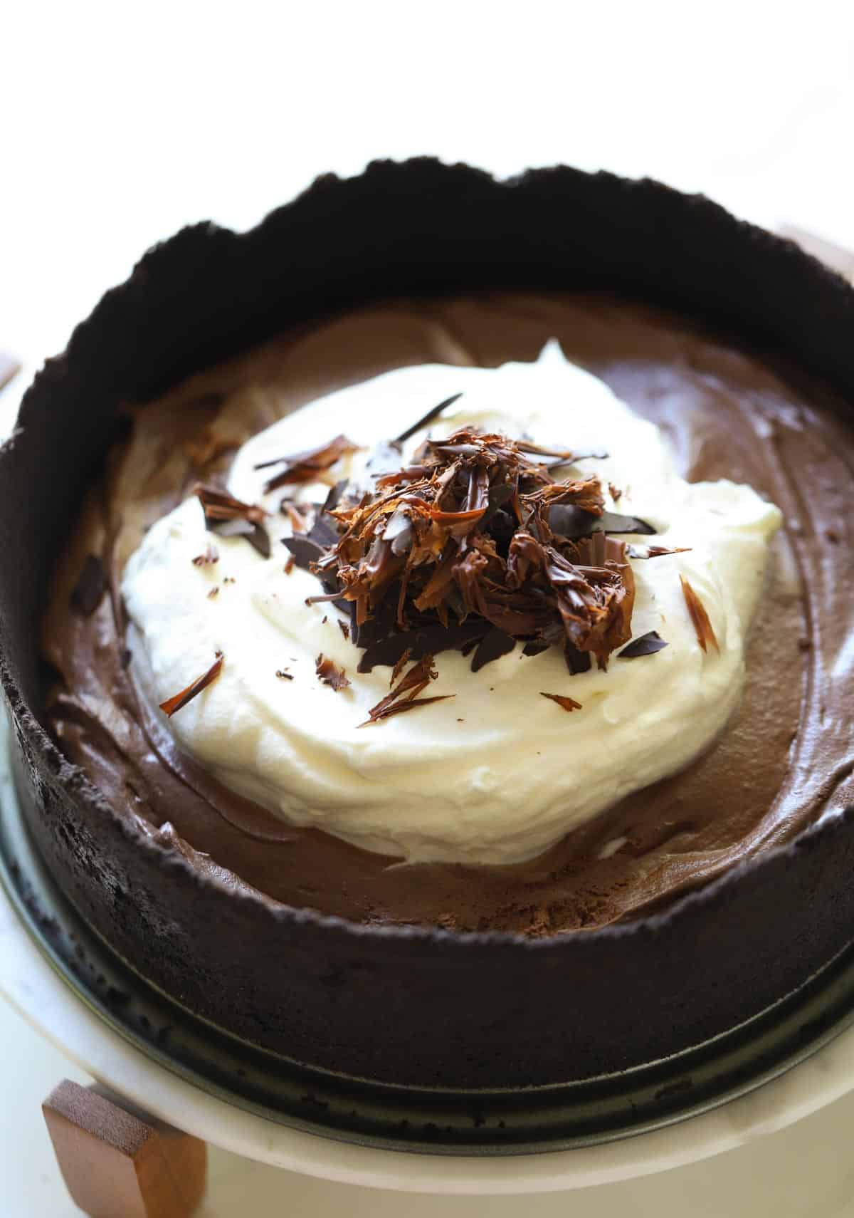 Chocolate Mousse Cake with whipped cream and shavings on a cake stand