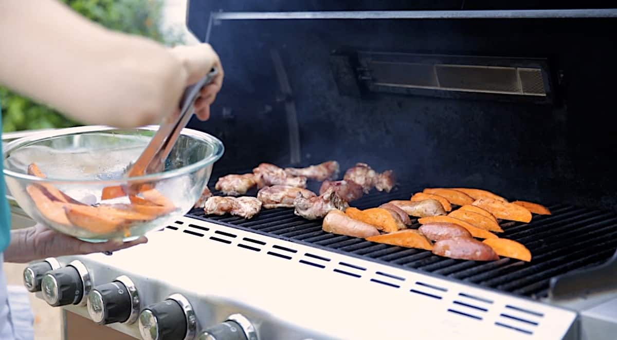 adding sweet potatoes to a grill with chicken