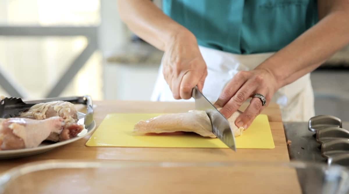 Cutting a raw chicken breast in half