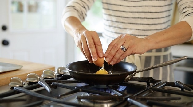 A person Cracking an egg in a pan