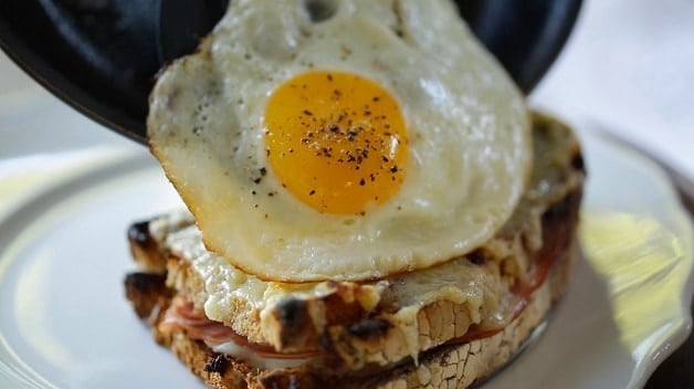 Sliding fried egg onto Croque Madame sandwich