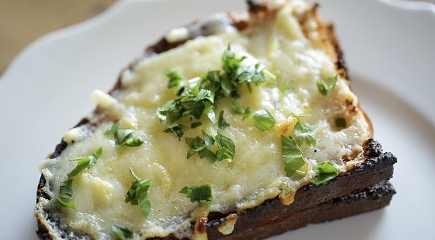 Close up of melted cheese on Croque Monsieur Sandwich garnished with fresh parsely