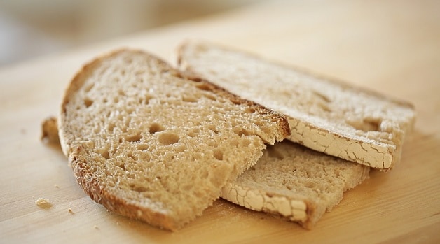 rustic sandwich bread sliced and stacked on a wooden cutting board