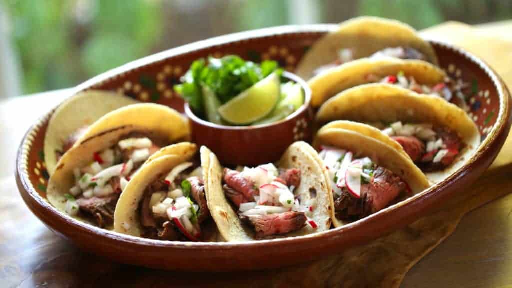 A terra-cotta platter filled with Carne Asada tacos