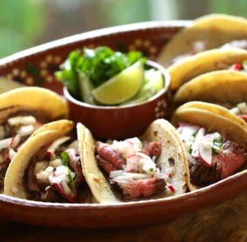 A terra-cotta platter filled with Carne Asada tacos