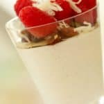 Panna Cotta in a glass topped with raspberries nuts and coconut