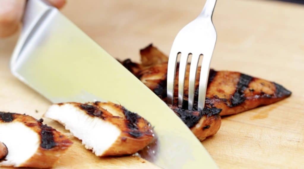 Slicing Teriyaki Chicken breast on a cutting board