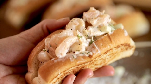 holding a New England Style Shrimp Roll in a split top bun in a Hand