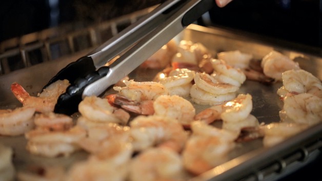 Shrimp in oven being tossed with tongs