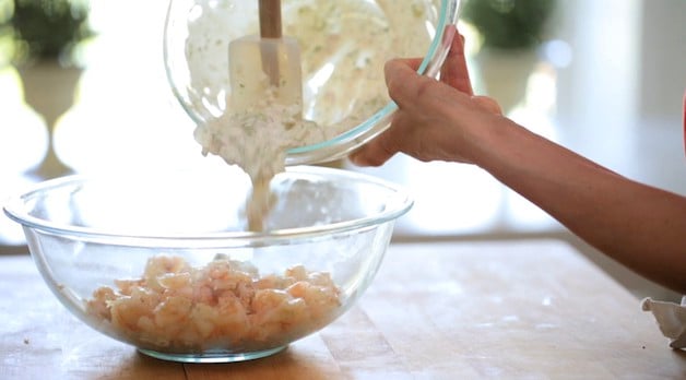 adding shrimp roll sauce to a bowl of cooked shrimp