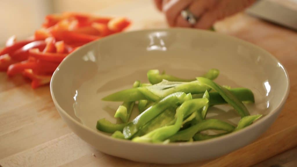 Red and Green Bell Peppers being sliced forEasy Cashew Chicken Recipe