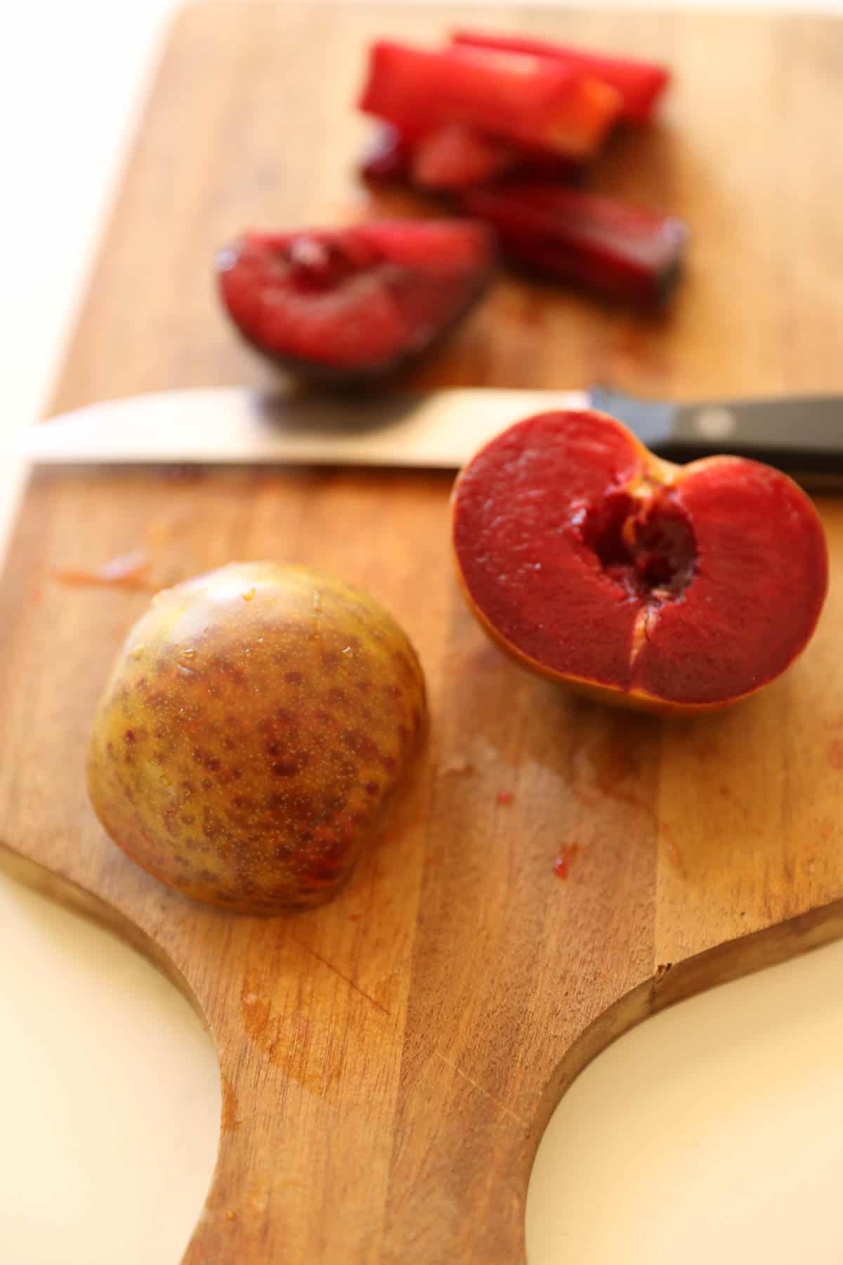 A sliced dinosaur plum on a cutting board