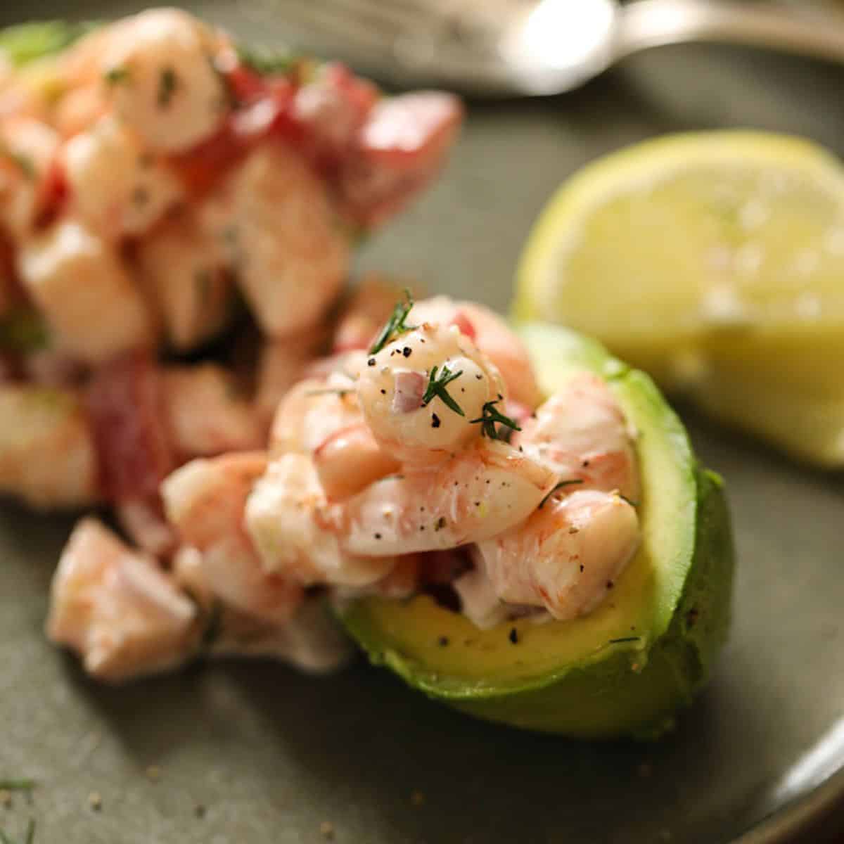 An avocado stuffed with shrimp salad on a plate.