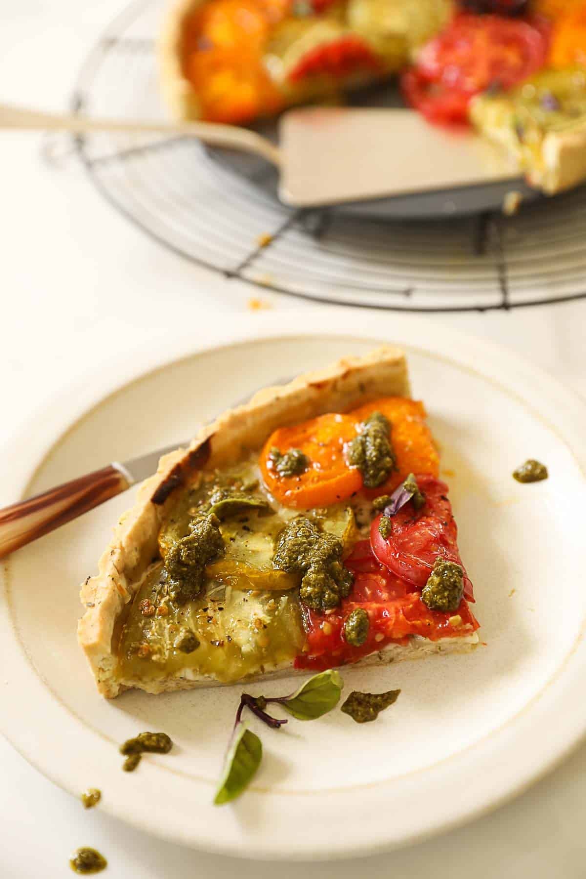 a slice of tomato tart with pesto on top.
