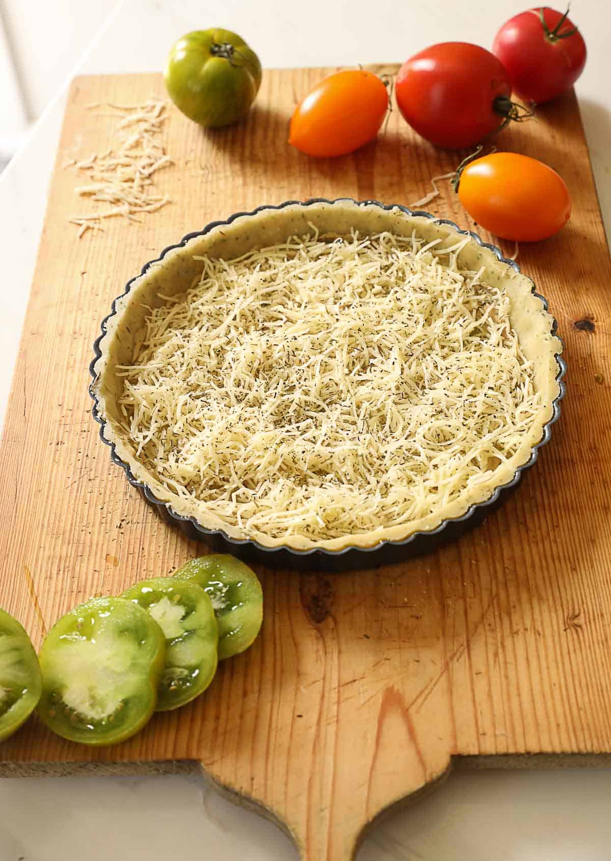 a tart tin filled with mustard and cheese on a cutting board with heirloom tomatoes.