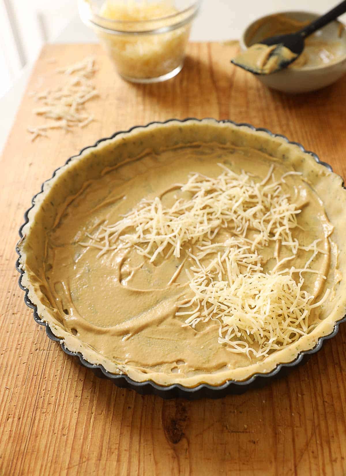 a tart tin with fitted pastry with mustard and cheese.