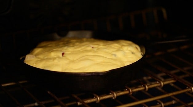 Batter mixture poured over berries in cast iron skillet in oven