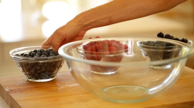 Large mixing bowl with smaller bowls in the background filled with berries