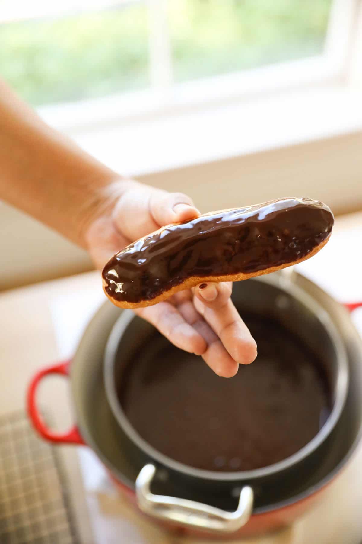 An eclair glazed with chocolate over a pot